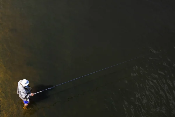 Un pescador en la orilla pesca con una caña de pescar — Foto de Stock