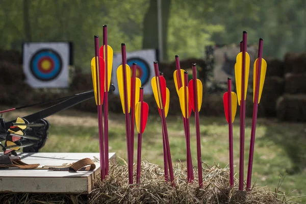 Tiro con arco y flechas de colores brillantes en un campo de tiro rústico al aire libre contra un fondo de pajar —  Fotos de Stock