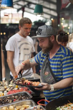 Ukrayna, Kiev, Belomorska Caddesi, 1 - 22 Temmuz 2017: sanat-zavod Platforma. Sokak gıda festival. Balık pazarı için çalışan bir erkeğin sıraya dizilmiş müşterilerine hizmet vermektedir.