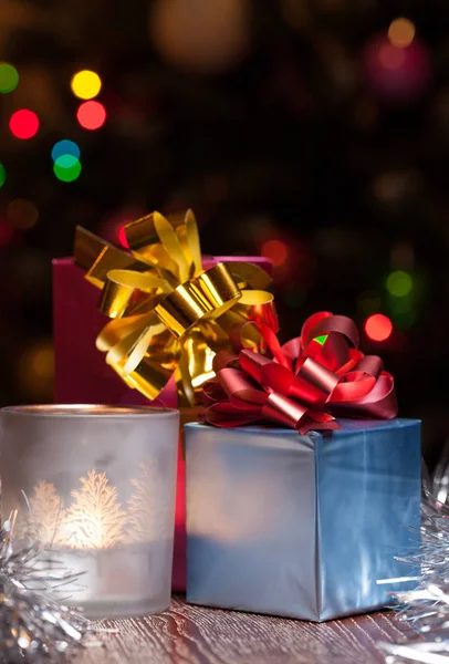 Scatola regalo colorata con candela e sfondo luci di Natale — Foto Stock