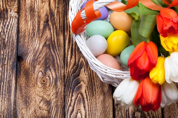Uova di Pasqua in un cesto bianco con tulipani colorati — Foto Stock