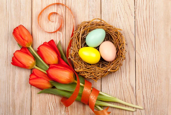 Ostereier im Vogelnest mit bunten Tulpen — Stockfoto