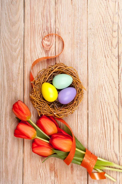 Uova di Pasqua in un nido di uccelli con tulipani colorati — Foto Stock