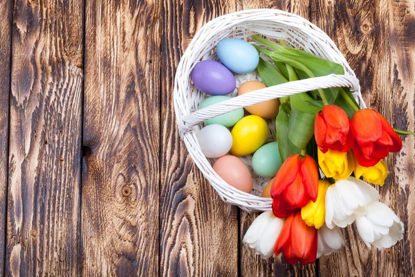 Uova di Pasqua in un cesto bianco con tulipani colorati — Foto Stock