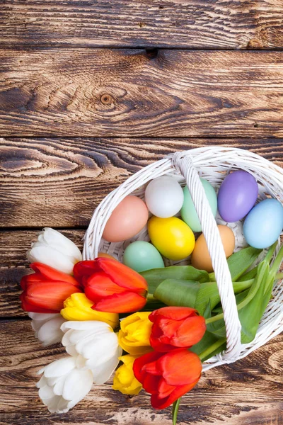 Uova di Pasqua in un cesto bianco con tulipani colorati — Foto Stock