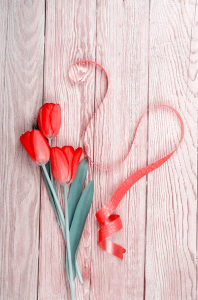 Červené tulipány na dřevěné pozadí s mašlí Royalty Free Stock Fotografie
