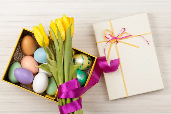 Easter Eggs in een doos met kleurrijke gele tulpen — Stockfoto