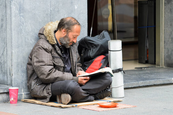 Человек, просящий милостыню, сидит на улице

