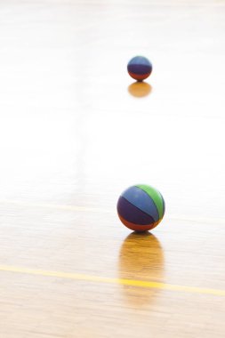 Spor salonunun parkesi üzerinde basketbol topları.