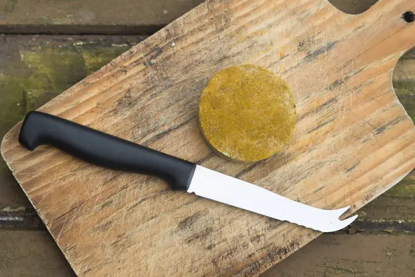 一块放在木板上的素食奶酪 旁边有一把刀 — 图库照片
