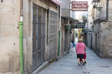 Pontevedra, İspanya - 16 Eylül 2017: Bir kadın şehrin tarihi merkezindeki kaldırımlı sokaklardan birinde bir alışveriş arabasını itiyor.
