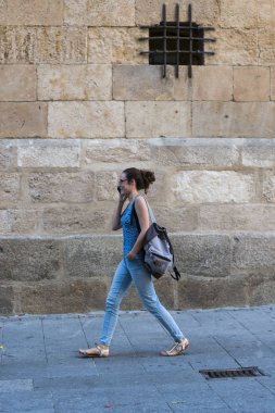 Salamanca, İspanya - 2 Eylül 2017: Şehrin tarihi merkezinde, sokakta yürürken genç bir kadın telefonla konuşuyor.