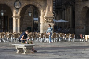 Salamanca, İspanya - 3 Eylül 2017: Barok tarzında, şehrin Plaza Belediye Başkanı 'nda bankta oturan bir kadın cep telefonunu kontrol ediyor..