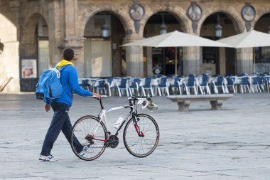 Salamanca, İspanya - 3 Eylül 2017: Bir adam, Barok tarzında, Plaza Mayor 'un merkezinde yürüyen bir bisikleti itiyor.