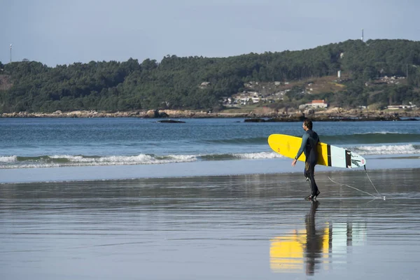 O GROVE, SPAIN - A surfer walks with his surfboard through the s — Stock Photo, Image