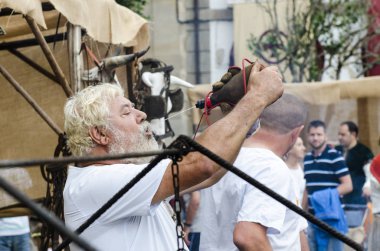 Pontevedra, İspanya - 6 Eylül 2014: Bir demirci, şehrin tarihi bölgesinde her yıl düzenlenen ortaçağ festivalinde, şarap tulumunda bir yudum şarap alır.