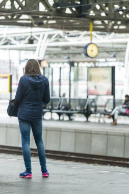 AMSTERDAM, NETHERLANDS - 8 HAZİRAN 2015: Kotlu bir genç, sırt, tren varış platformunda duruyor.