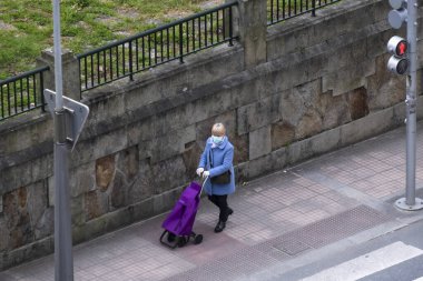 PONTEVEDRA, İspanya - 28 Mart 2020: Koronavirüs salgını nedeniyle alarm durumunda, alışveriş arabası ve maskeli bir kadın.