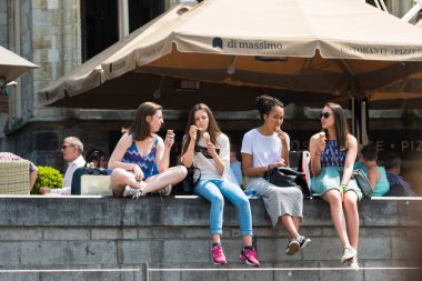 GHENT, BELGIUM - 3 HAZİRAN 2015: Dondurma yiyen bir grup kız, kenti geçen kanallardan birinin yanında oturuyorlar.