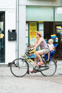 MECHELEN, BELGIUM - 5 HAZİRAN 2015: Bir anne bisikletle şehrin sokaklarından birinde yürüyor.
