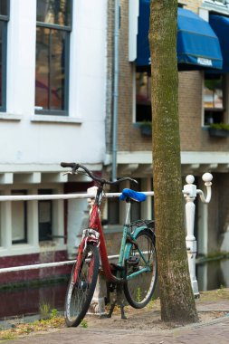 DELFT, NETHERLANDS - 6 HAZİRAN 2015: Bir bisiklet yeşili ve kırmızı renk, çok karışık, köy kanallarından birinin parmaklıklarında park edilmiş.