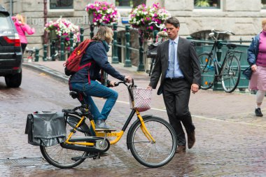 AMSTERDAM, NETHERLANDS - 8 HAZİRAN 2015: Takım elbiseli bir adam, bisiklete binen bir kadından kaçıyor, bu da neredeyse ona çarpıyordu..