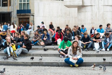 AMSTERDAM, NETHERLANDS - 8 Temmuz 2015: Şehrin merkez meydanında, bir merdivende oturan büyük bir grup insan.