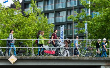 AMSTERDAM, NETHERLANDS - 8 HAZİRAN 2015: Motorların park edildiği kanallardan birinin üzerinden geçen insanlar.