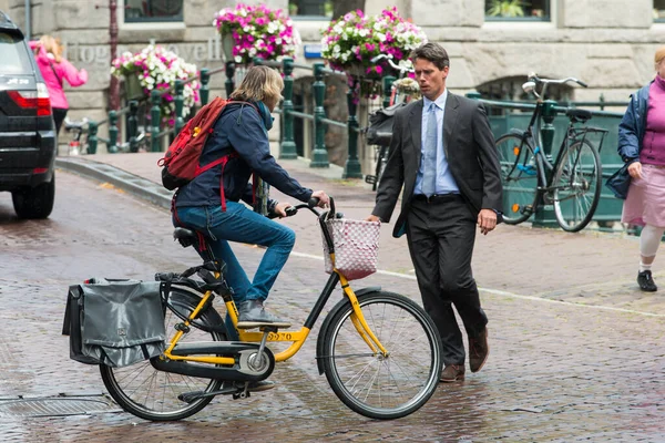 AMSTERDAM, NETHERLANDS - 8 HAZİRAN 2015: Takım elbiseli bir adam, bisiklete binen bir kadından kaçıyor, bu da neredeyse ona çarpıyordu..