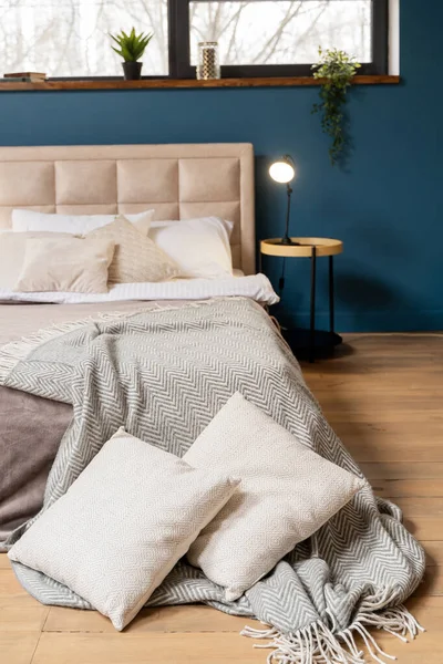 bedroom with a dark blue wall. bedside tables with lamps and clocks on