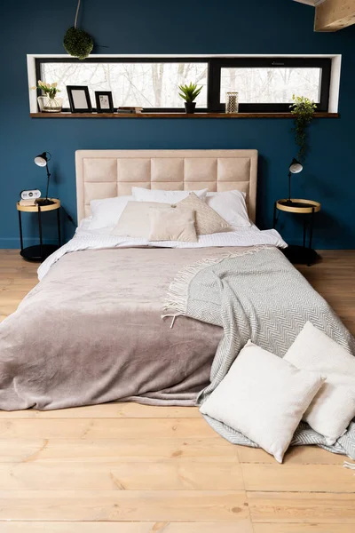 bedroom with a dark blue wall. bedside tables with lamps and clocks on