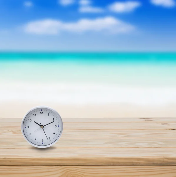 Clock on wood table and blue sea background
