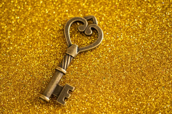 Vintage klucz na tle złoty brokat — Zdjęcie stockowe