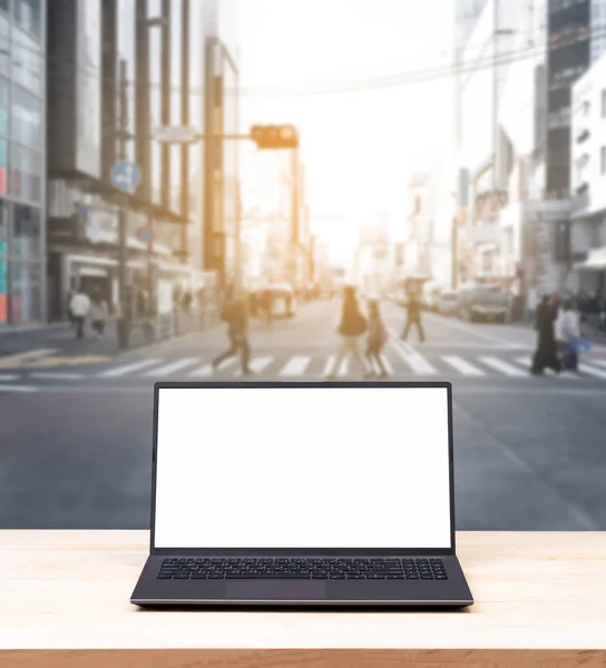 Blank white screen laptop computer with blurred street view — Stock Photo, Image