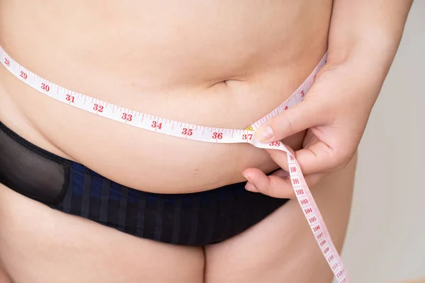 Nadváha ženy s páskou měření její břicho — Stock fotografie