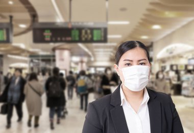 Gribi önlemek için cerrahi maske takan Asyalı bir kadın. Corona virüsü. Kalabalığın bulanık görüntüsü.