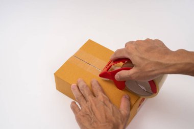 Adam elleri bant ile paket kutusu paketliyor.