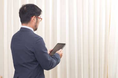 Dijital tablet bilgisayarda çalışan Asyalı adamın arka tarafı.