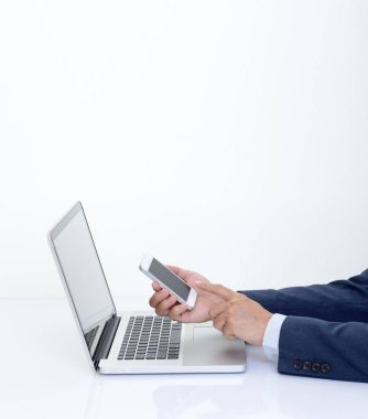 İşadamı dizüstü bilgisayarla akıllı telefonu tutuyor