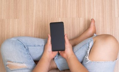 Kadın ellerinin boş ekranlı cep telefonu tuttuğu en üst görüntü. çalışma formu ev kavramı