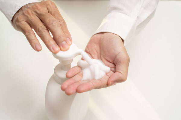 Hand sanitizer soap foam clean hands hygiene prevention of corona virus outbreak. Man using bottle of antibacterial sanitiser soap. covid-19