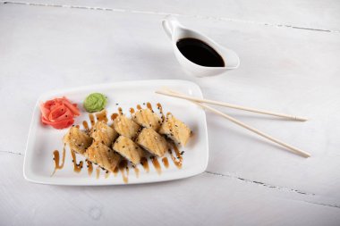 Japon yemekleri soya soslu beyaz tabakta yuvarlanıyor.