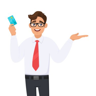Kredi kartı tutan ya da gösteren genç bir iş adamı (ATM, ATM) ve el hareketi işareti sunan bir şey. Erkek karakter tasarımı çizimi. Vektör karikatür biçiminde modern yaşam tarzı kavramı.