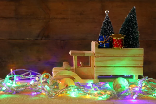 Houten auto uitvoering een kerstboom naast garland lichten — Stockfoto
