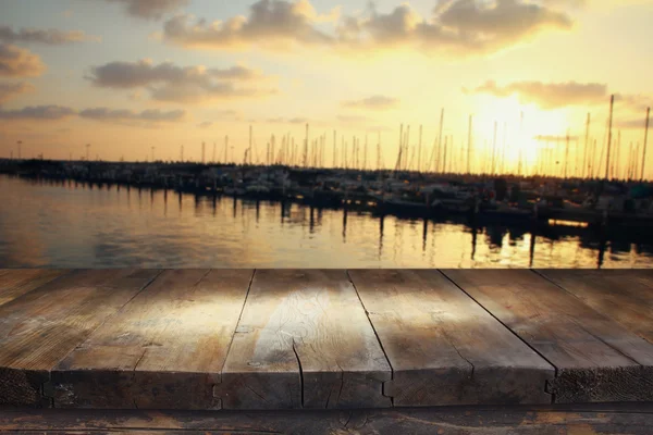 Holztisch vor verschwommenen Yachten im Pier bei Sonnenuntergang — Stockfoto