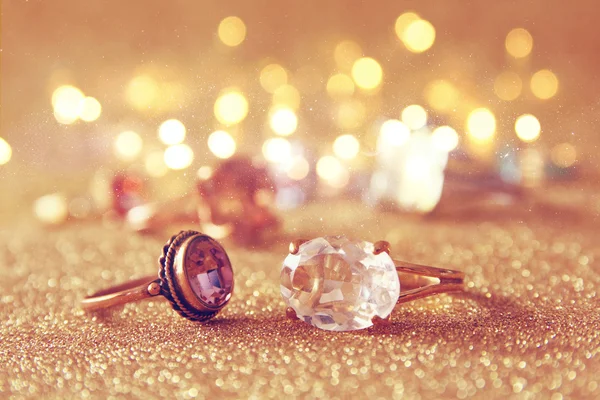 Image of elegant gold rings on gold glitter background — Stock Photo, Image