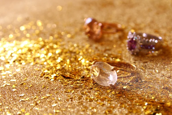 Image of elegant gold rings on gold glitter background — Stock Photo, Image