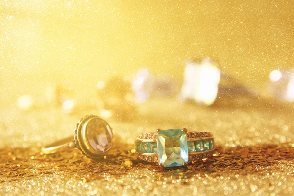 Wizerunek eleganckie złote pierścienie na tle złoto świecidełka — Zdjęcie stockowe