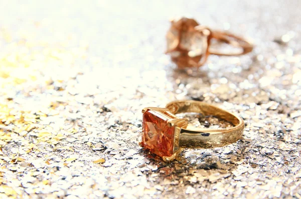 Eleganckie złote pierścienie na złoty i srebrny brokat tło. — Zdjęcie stockowe