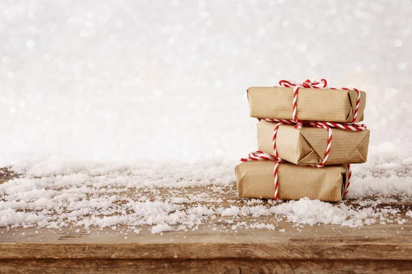 Cajas de regalo hechas a mano sobre mesa de madera nevada — Foto de Stock